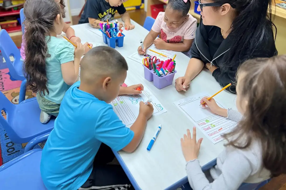 Pre-K children working on paper homework activities supporting parent-teacher partnership and consistent skill…