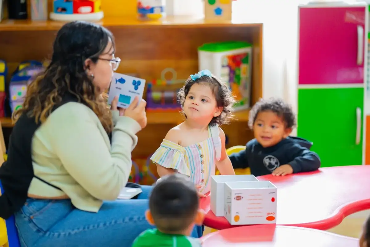 Teacher playing a musical instrument and demonstrating it to children during songs and creative play at Newport Ave Preschool