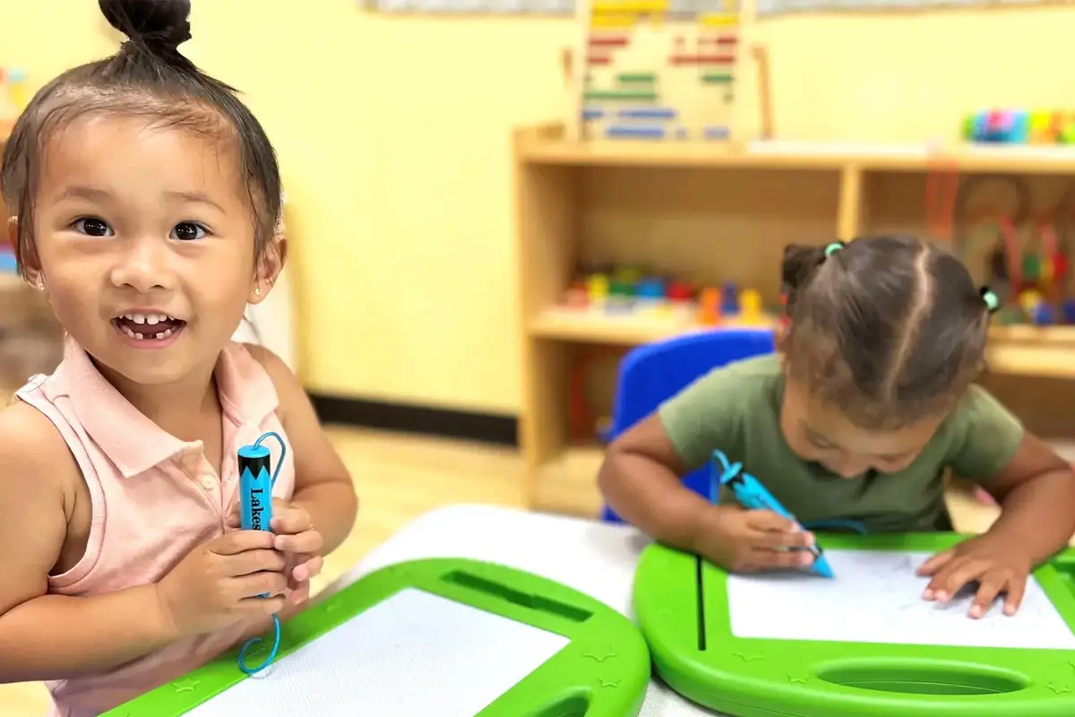 Young children sharing materials and collaborating on an art activity while developing social skills and independence at…