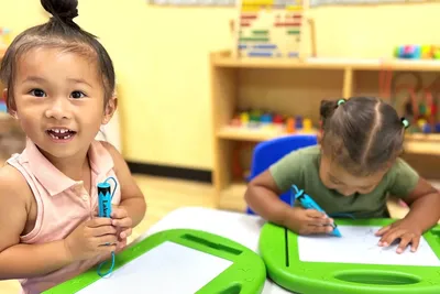 Young children sharing materials and collaborating on an art activity while developing social skills and independence at Newport Ave Preschool